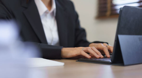 A company secretary writing a meeting note in her computer