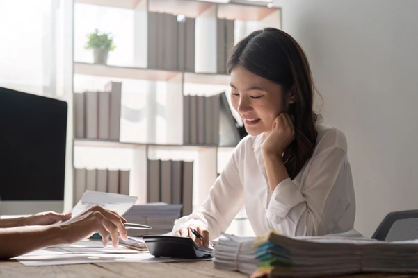 A woman planning for Singapore tax payment using a calculator and documents