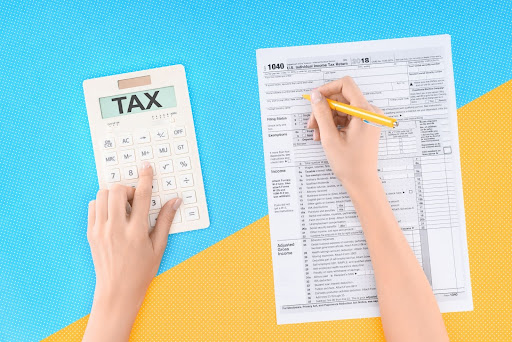 A person using a calculator while filling out a tax form