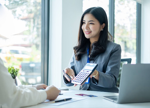 A female tax professional in an office, holding a calculator and explaining corporate tax preparation to a client