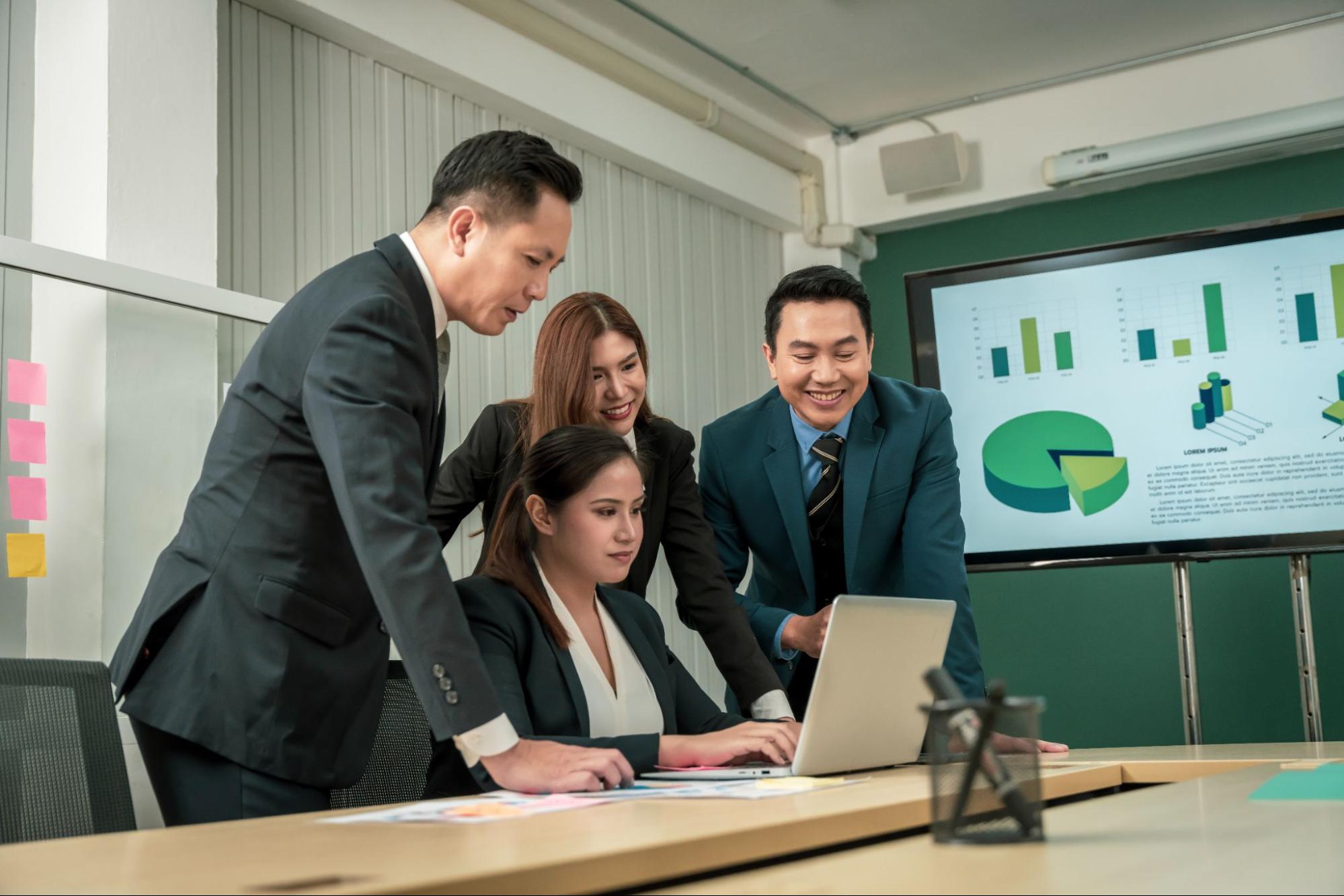 Confident modern Asian businessman reviewing monthly financial reports and cash flow statements at desk