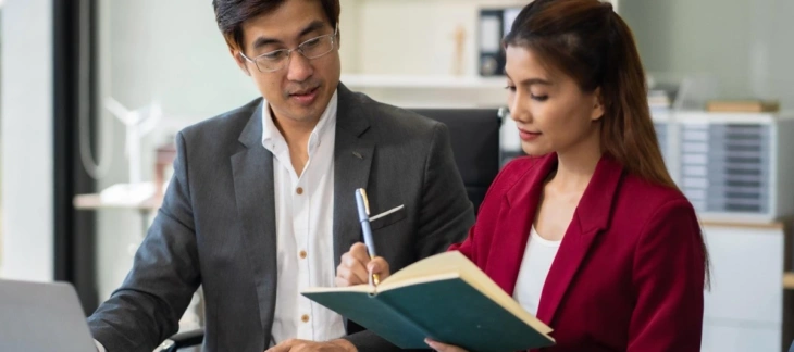 Two corporate professionals in a Singapore office discussing company compliance and ACRA filing requirements.